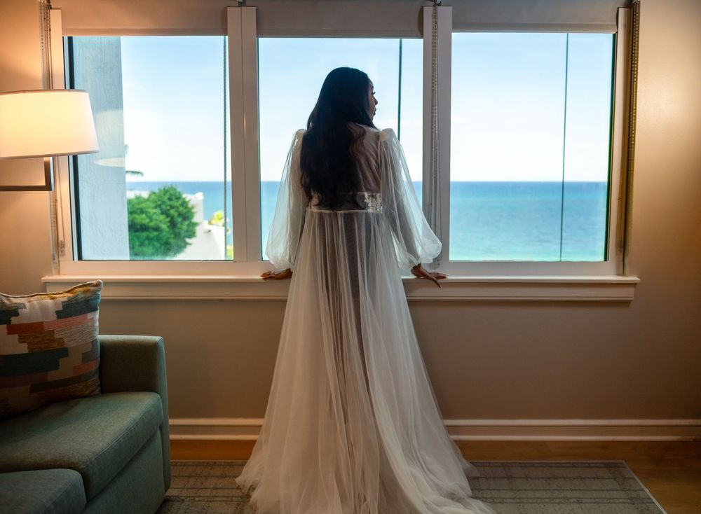 The bride is framed in an ocean front view from her hotel suite.