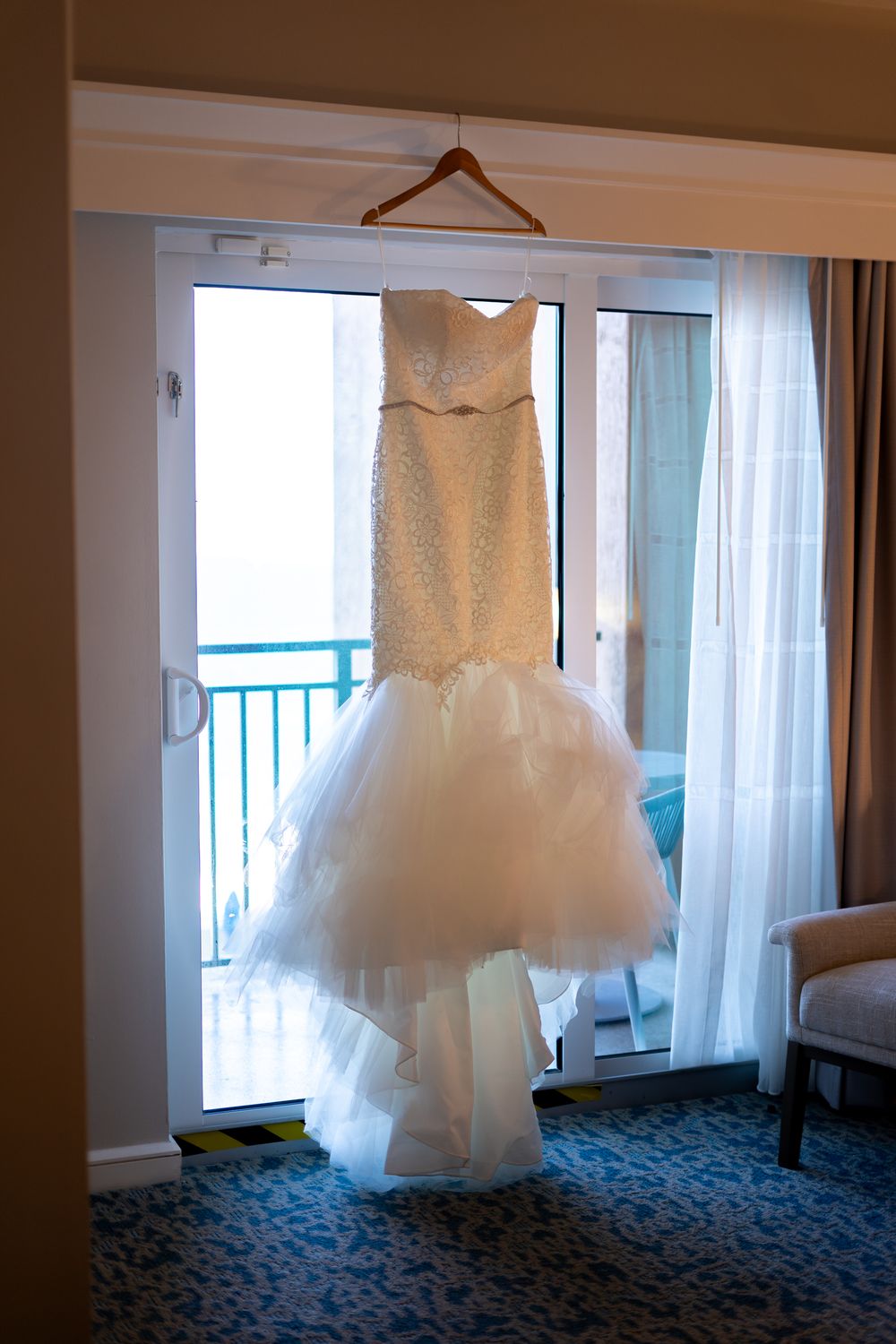 Bride's dress hangs over the balcony door.
