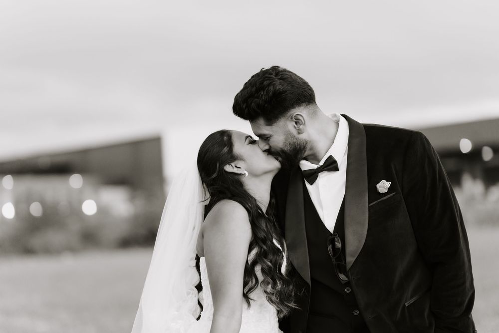 Black and white photo of a bride and groom sharing a romantic kiss on their wedding day.