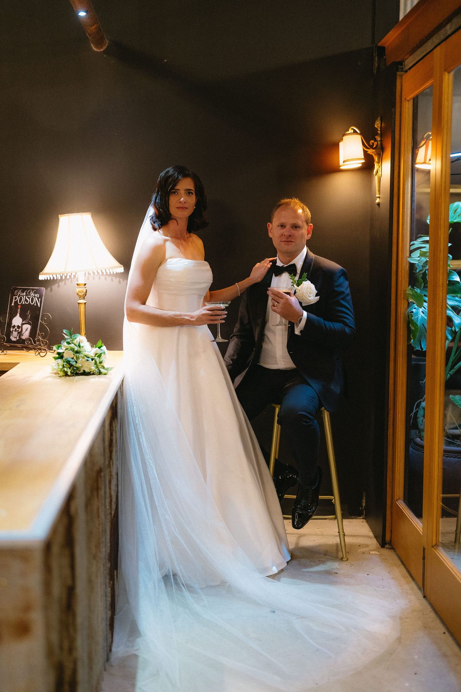 Bride and groom share a romantic dip kiss under a crystal chandelier in an elegant rustic wedding venue.