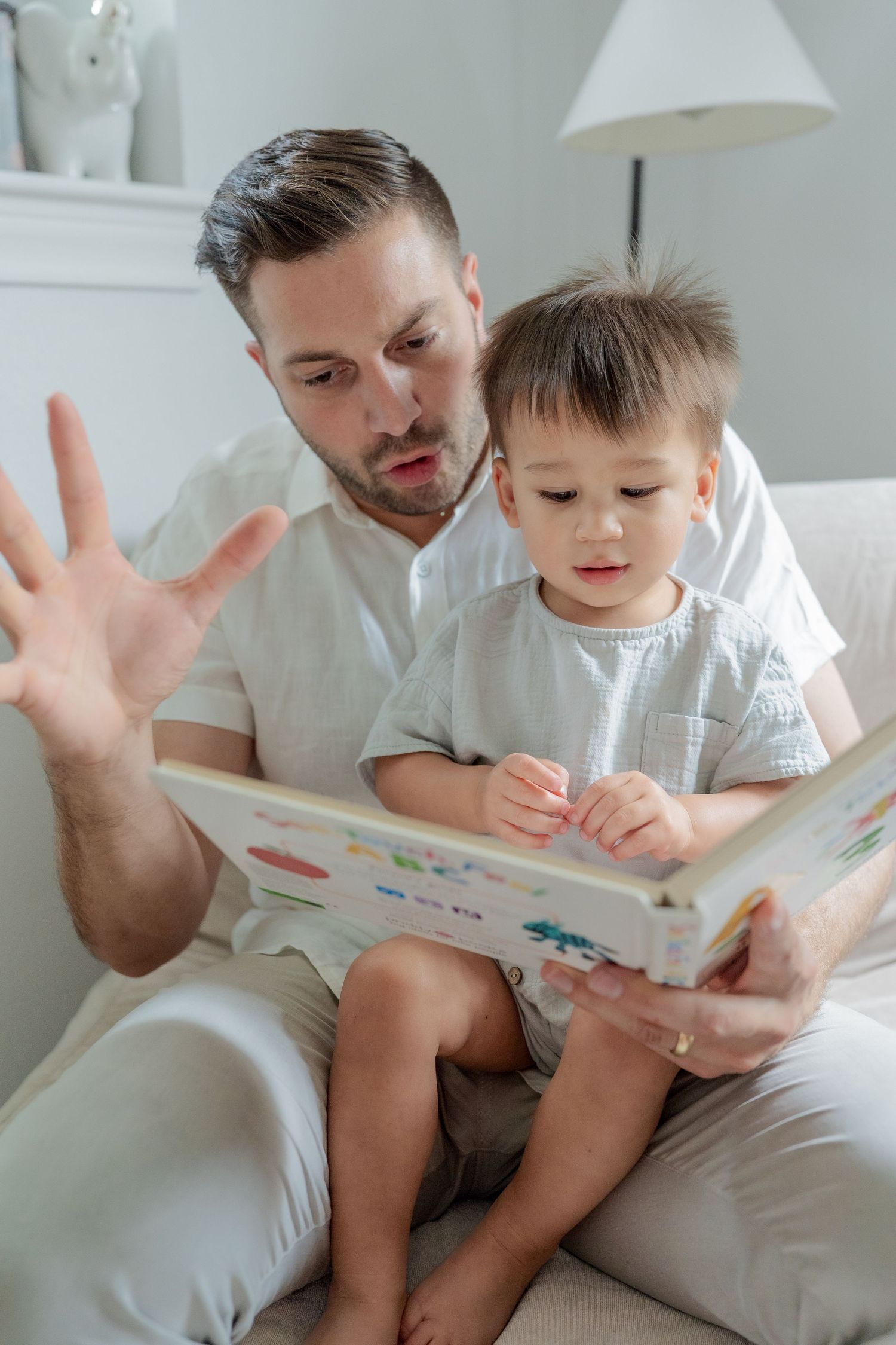 Dad reading toddler a book in nursery