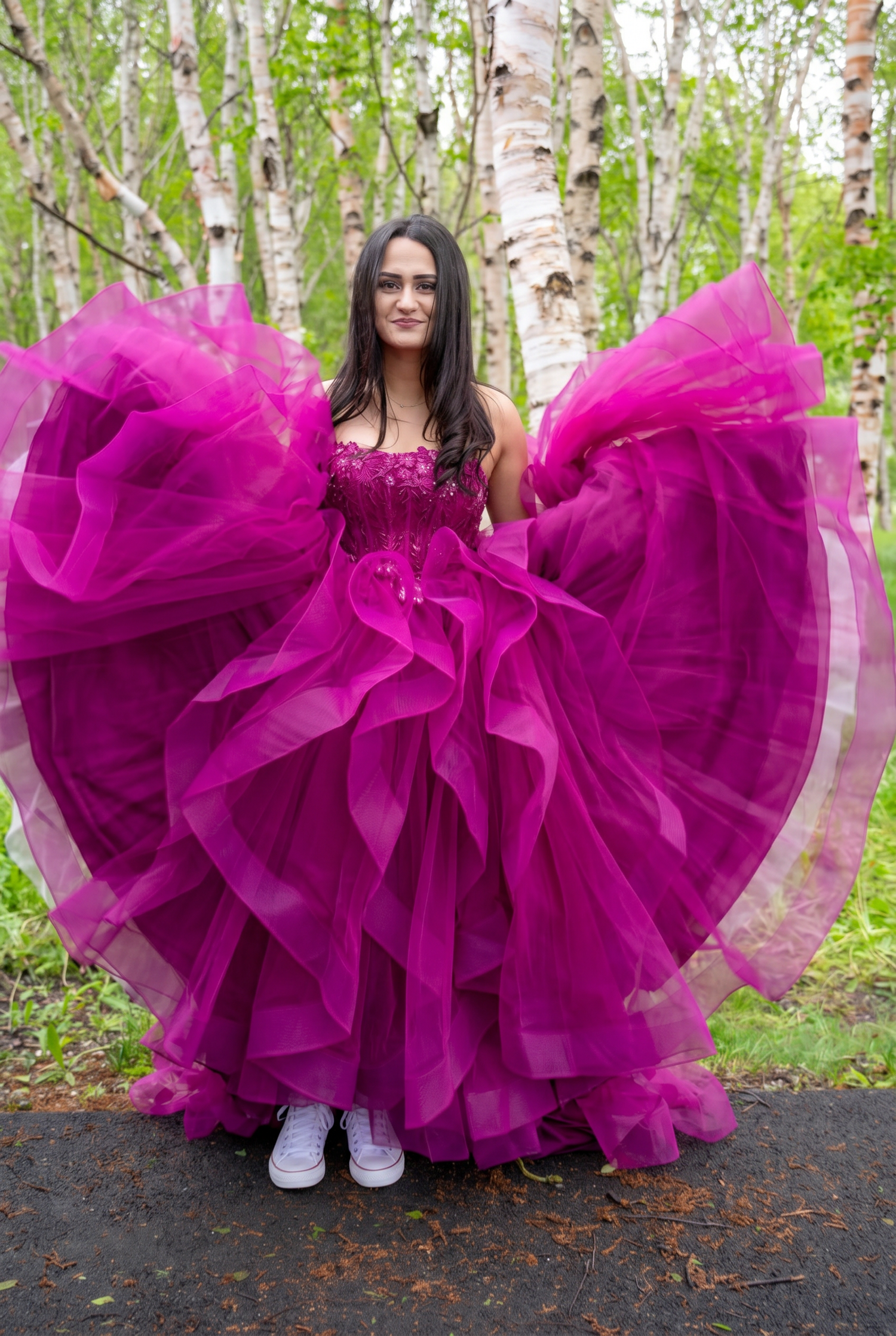Young woman in elegant gray ombre ball gown posing on a tree-lined dirt path.
