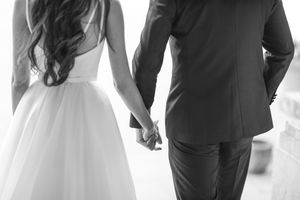 Black and white photo of a bride and groom holding hands at their wedding ceremony.