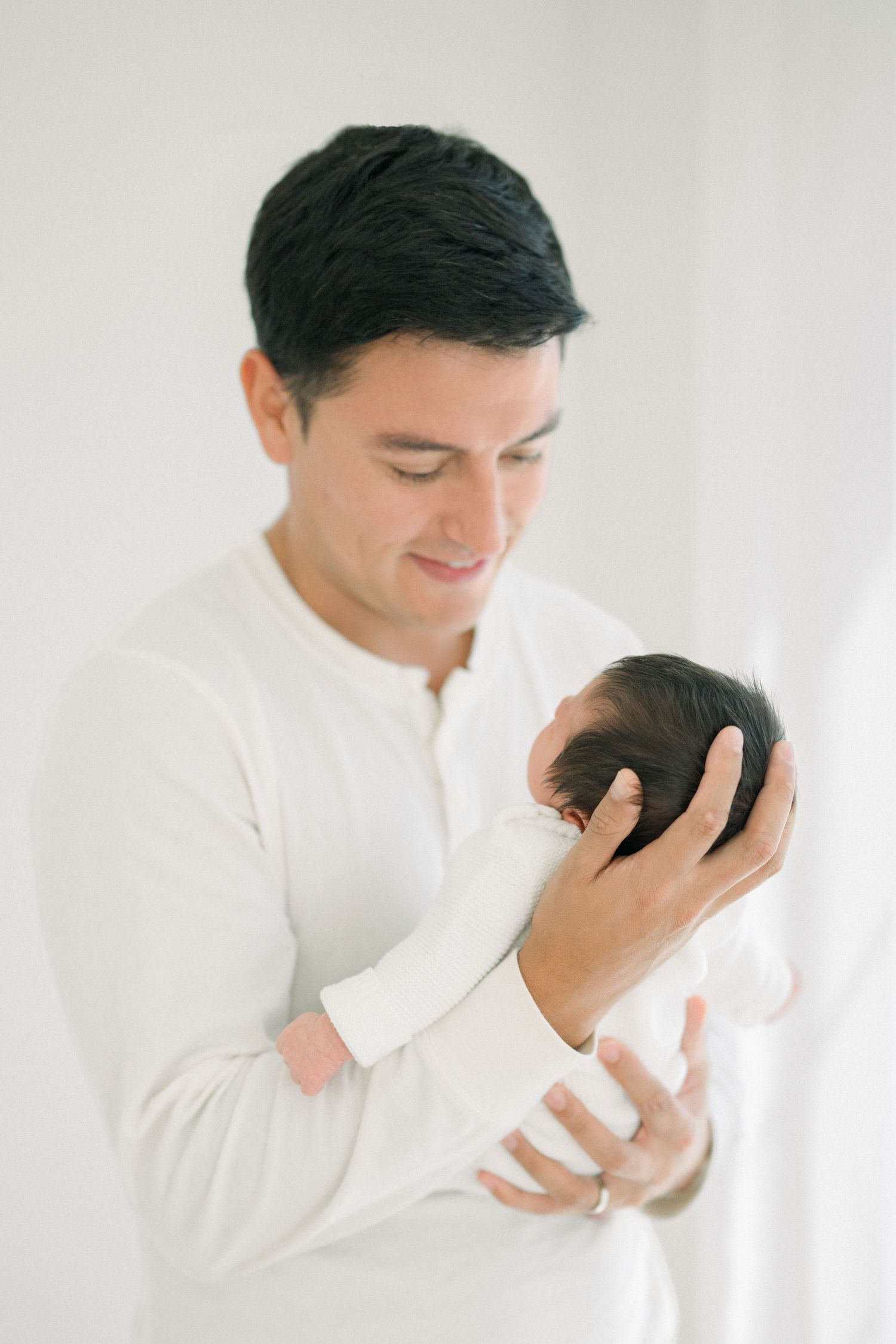 a father in white looks at his baby at an in-home newborn session on Capitol Hill