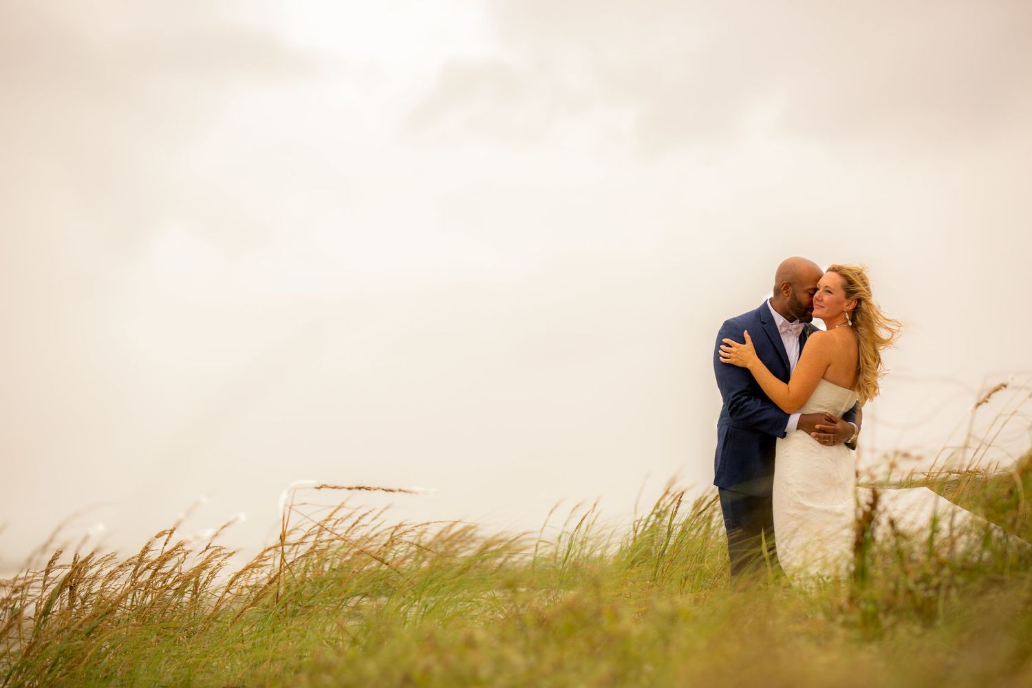 Romantic beach proposal with man on one knee holding hands with woman on sandy shore near ocean waves.