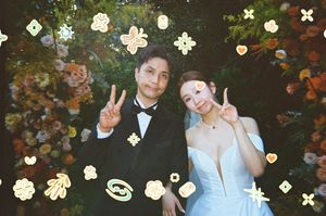 Couple in formal wedding attire posing with peace signs among floral decorations and festive stickers.