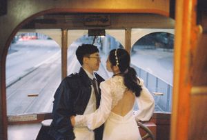 Bride and groom share a romantic moment aboard a vintage wooden trolley car on their wedding day.