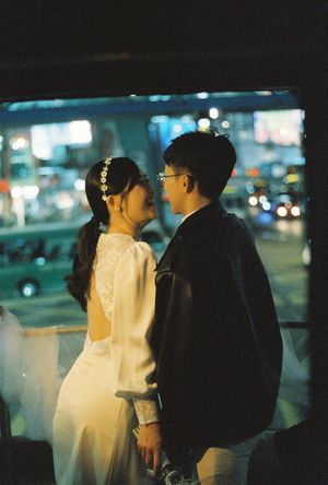 Couple in wedding attire sharing a romantic moment at night with city lights bokeh in the background.