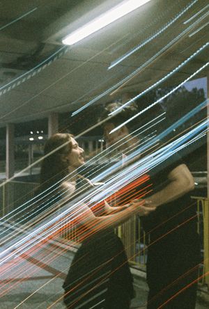 Long exposure photo of two people with colorful light trails streaking across them in blue, red, and white.