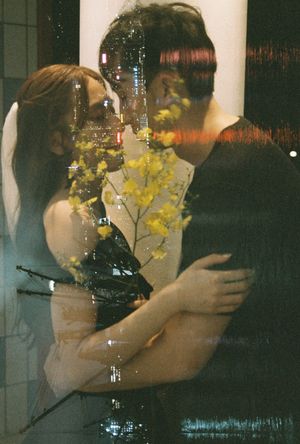 Couple embracing romantically in a double exposure photo with yellow flowers and city lights.