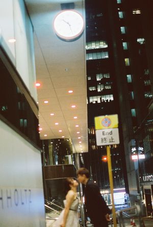 Nighttime urban street scene in Asia with a wall clock, illuminated ceiling, and bilingual End sign on a busy city block.