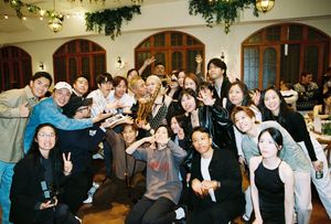 Large group of smiling Asian friends posing together at an indoor celebration party venue with festive decorations.