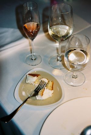 Elegant table setting with three wine glasses and a dessert plate with cake and fork on white linen.
