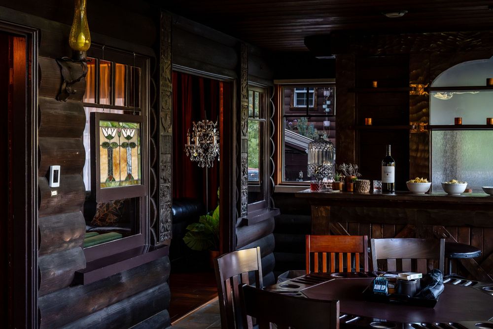 Dark wood interior of an upscale restaurant with stained glass windows, dining table, and moody atmospheric lighting.