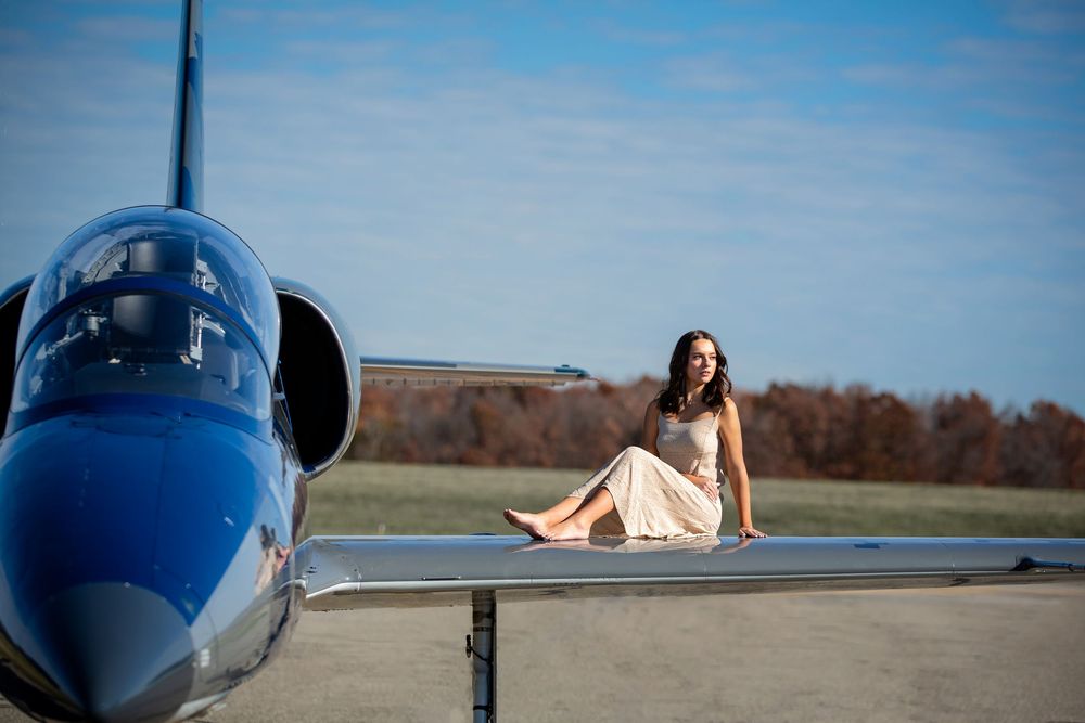 High school senior girl posing on jet plane at private airport in Howell Michigan; senior aviation photos by South Lyon, MI photographer