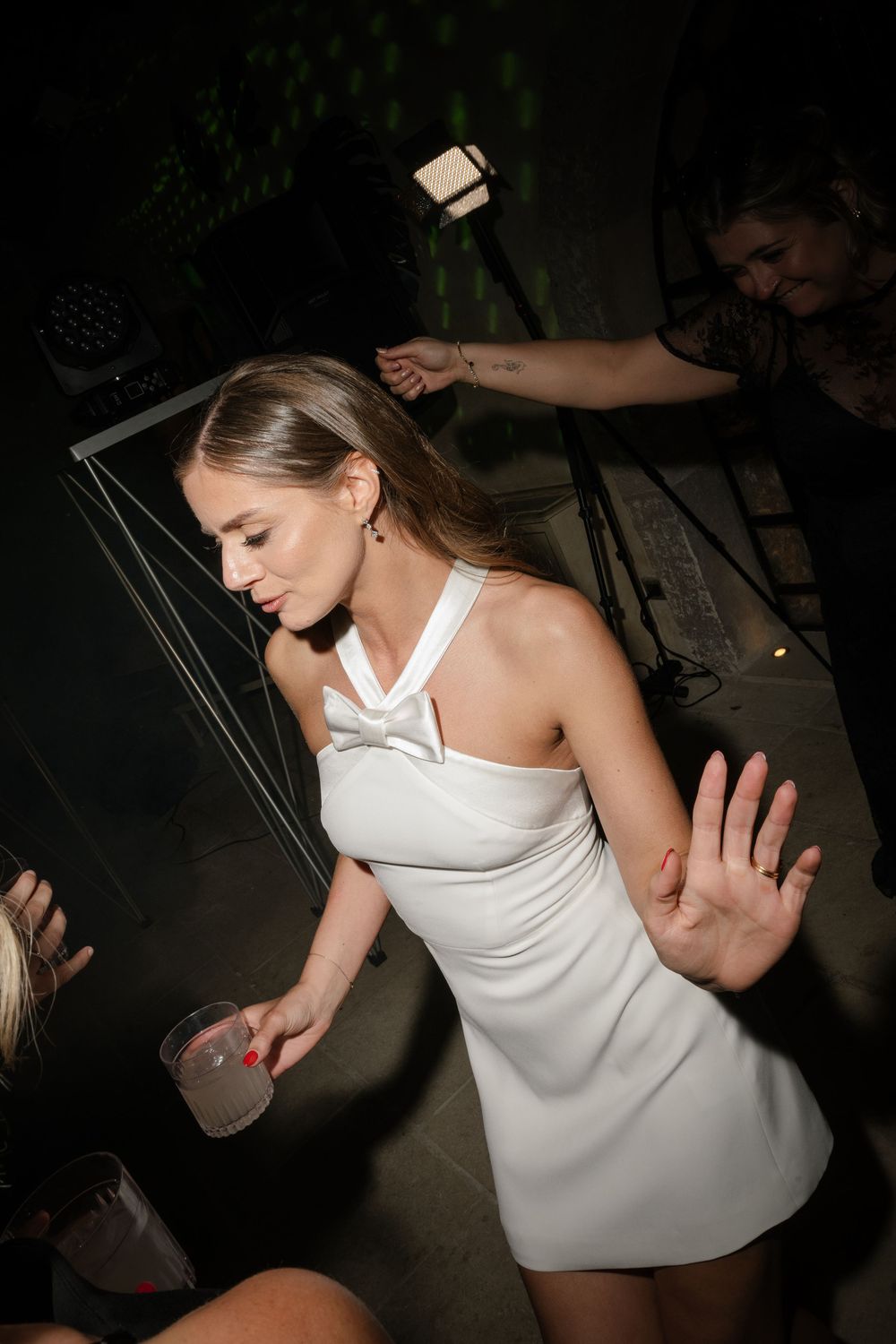 Young woman in white mini dress dancing at a nightclub party event.
