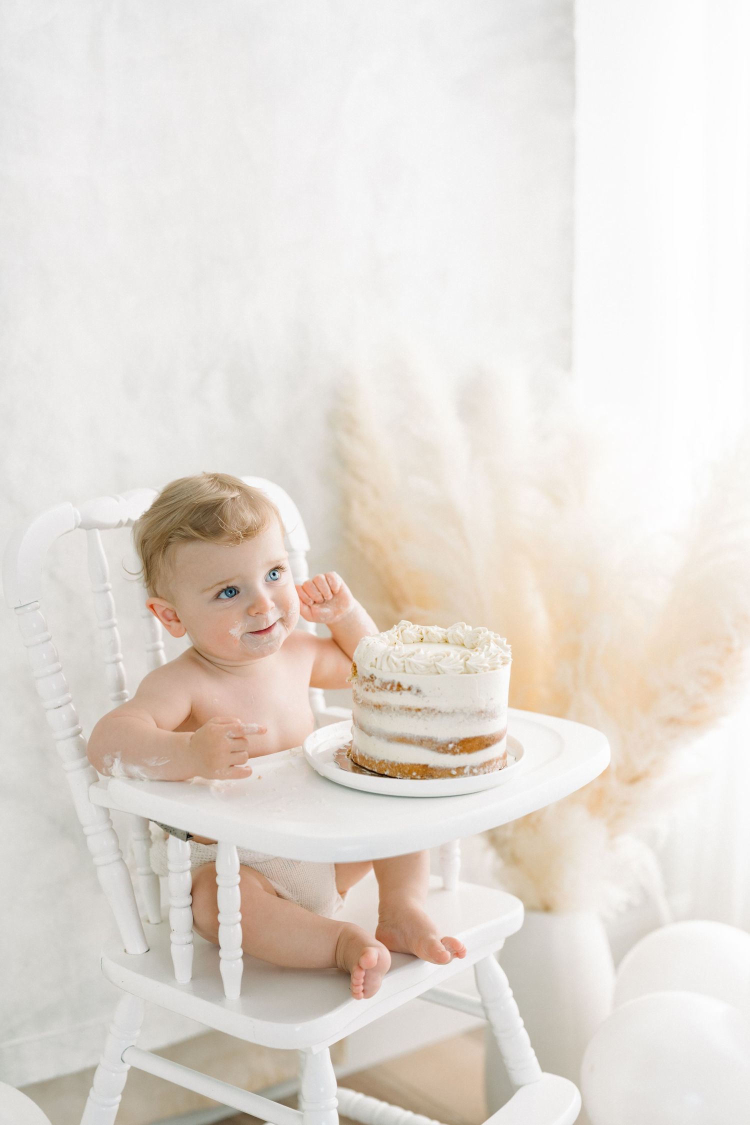 Bébé célébrant son premier anniversaire au studio de Québec avec une séance photo smash the cake (cake smash) dans une chaise haute antique