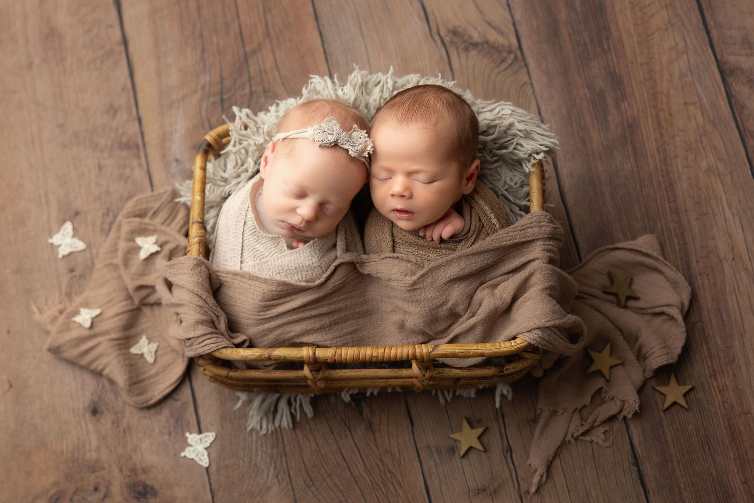 Peaceful newborn baby swaddled in cream wrap sleeping on soft beige blanket during professional newborn photography session.