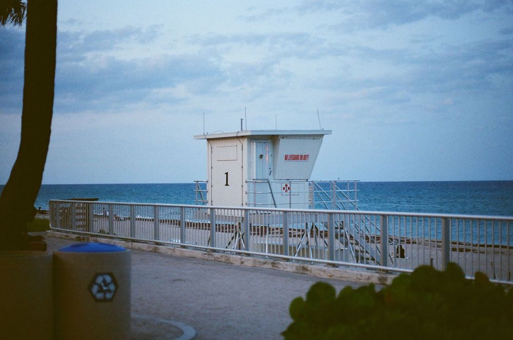 Lifeguard station number 1 on a sunny beach with blue ocean waters and cloudy skies in the background.