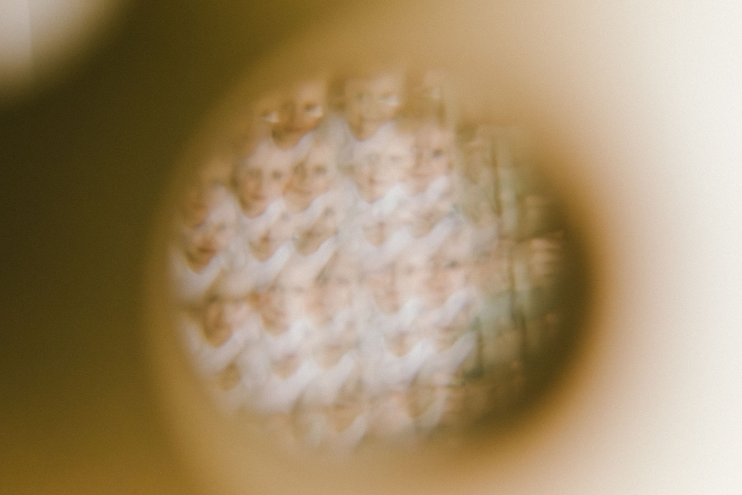 Blurry macro photo of a textured woven fabric surface viewed through a circular lens with soft bokeh effect.
