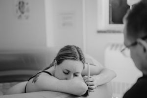 Woman resting her head on her arms during labor, black and white birth photography.