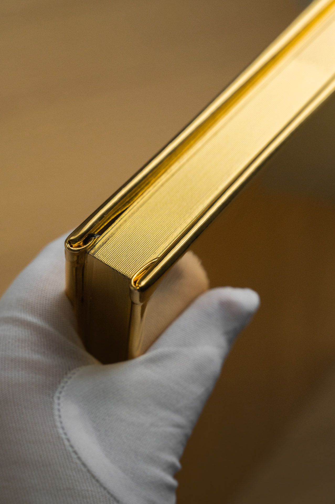 Gloved hand holding a luxurious gold metallic spine hardcover Love Stories photo book.