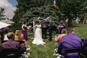 Bride and groom exchange vows under floral arch at intimate outdoor garden wedding ceremony.