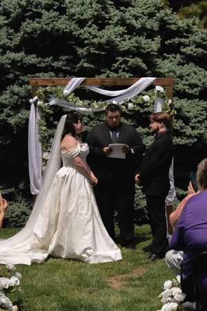 Bride and groom exchange vows at outdoor wedding altar decorated with white florals.