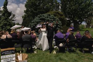 Newlyweds celebrating joyfully as they walk back down the aisle after outdoor wedding ceremony.