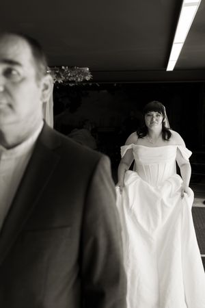 Black and white photo of bride in white off-shoulder gown preparing to walk down the aisle with escort.