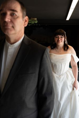 Bride in white corset wedding gown smiles behind her escort before walking down the aisle.
