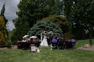 Small intimate outdoor wedding ceremony with guests seated on chairs in a lush garden.
