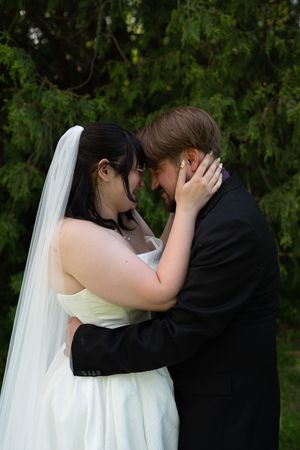 Bride and groom touch foreheads tenderly in romantic outdoor wedding portrait.