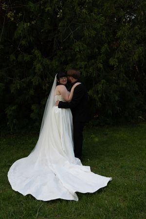 Bride and groom share romantic moment in garden, bride wearing long veil and white gown.