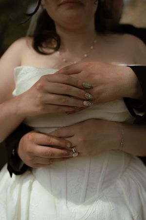Close-up of bride and groom hands, bride wearing diamond ring and decorative nail art.