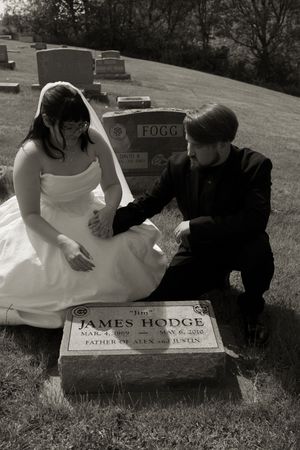 Bride and groom in black-and-white photo pay respects at James Hodge gravestone during wedding day memorial visit.