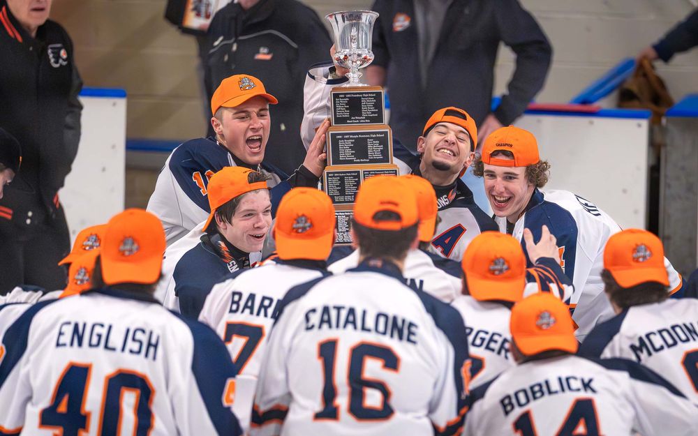 Hershey Trojans celebrate on ice wearing orange hats after winning the Flyers Cup by Deanna Fox, SportsFox Photography based in Hershey PA.