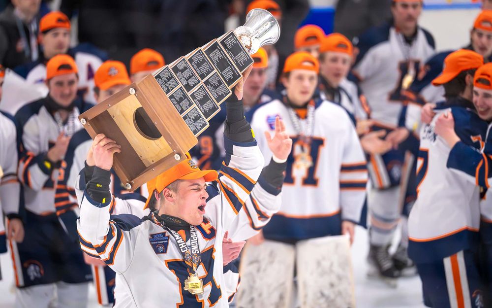 Hershey Trojan players hoist the Flyers Cup trophy in celebration on the ice by Deanna Fox, SportsFox Photography based in Hershey PA.