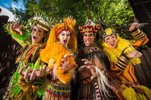Costumed performers in vibrant animal-inspired outfits performing in a theatrical production.