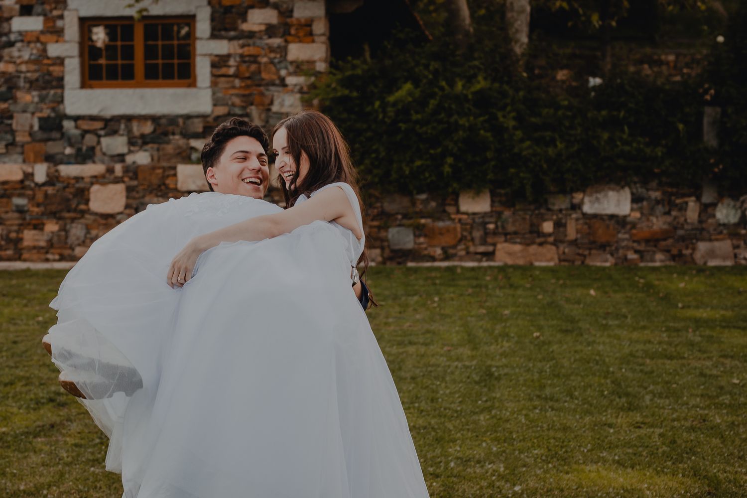 Elegant outdoor wedding ceremony setup with stone walls and natural landscaping.