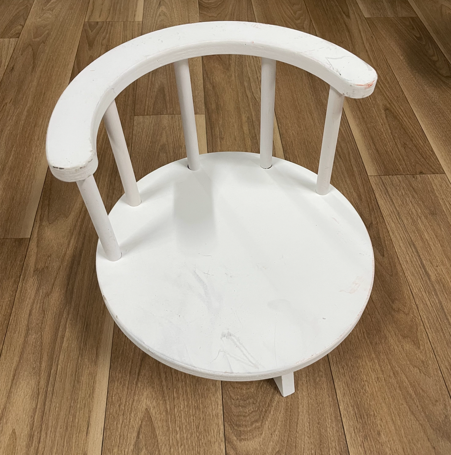White painted wooden chair back shown in progressive angles on hardwood floor.