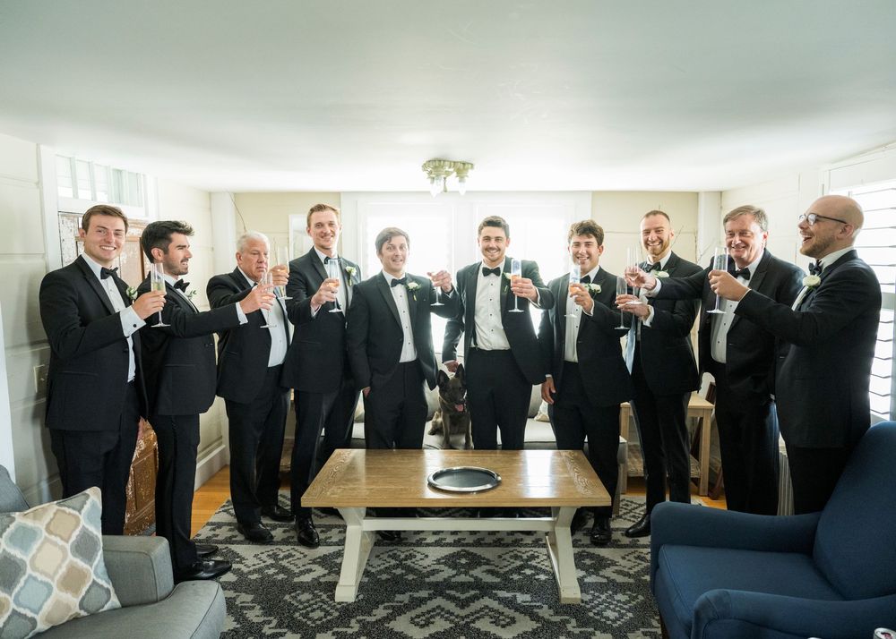 A panoramic sequence showing groomsmen in black suits getting ready and posing in a bright hotel room.