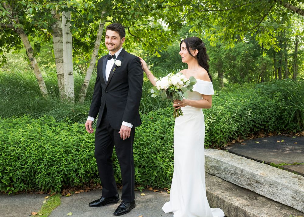 First look moment captured between bride and groom on garden steps outdoors.