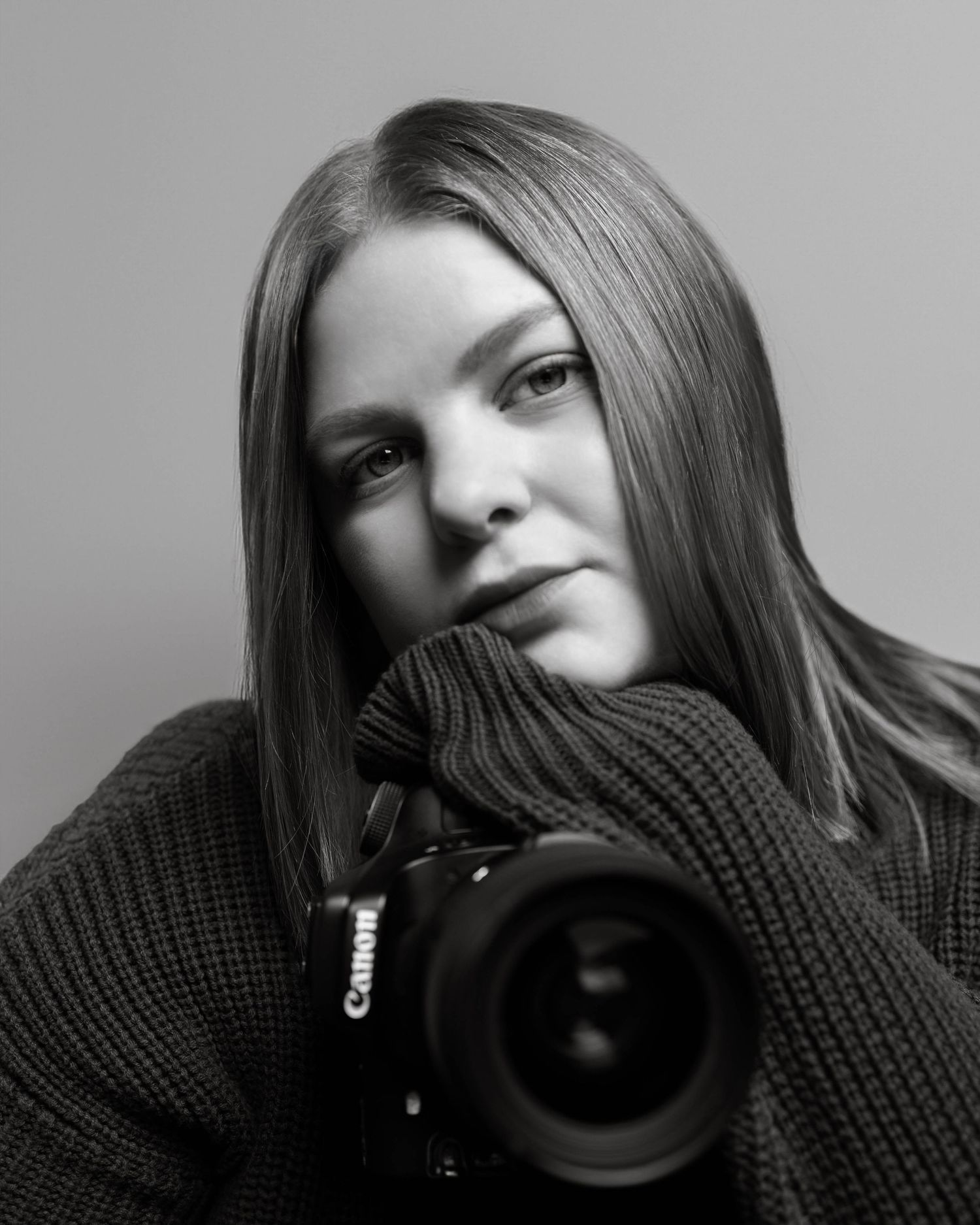 Professional black and white portrait with Canon camera and photographer wearing a knit sweater.