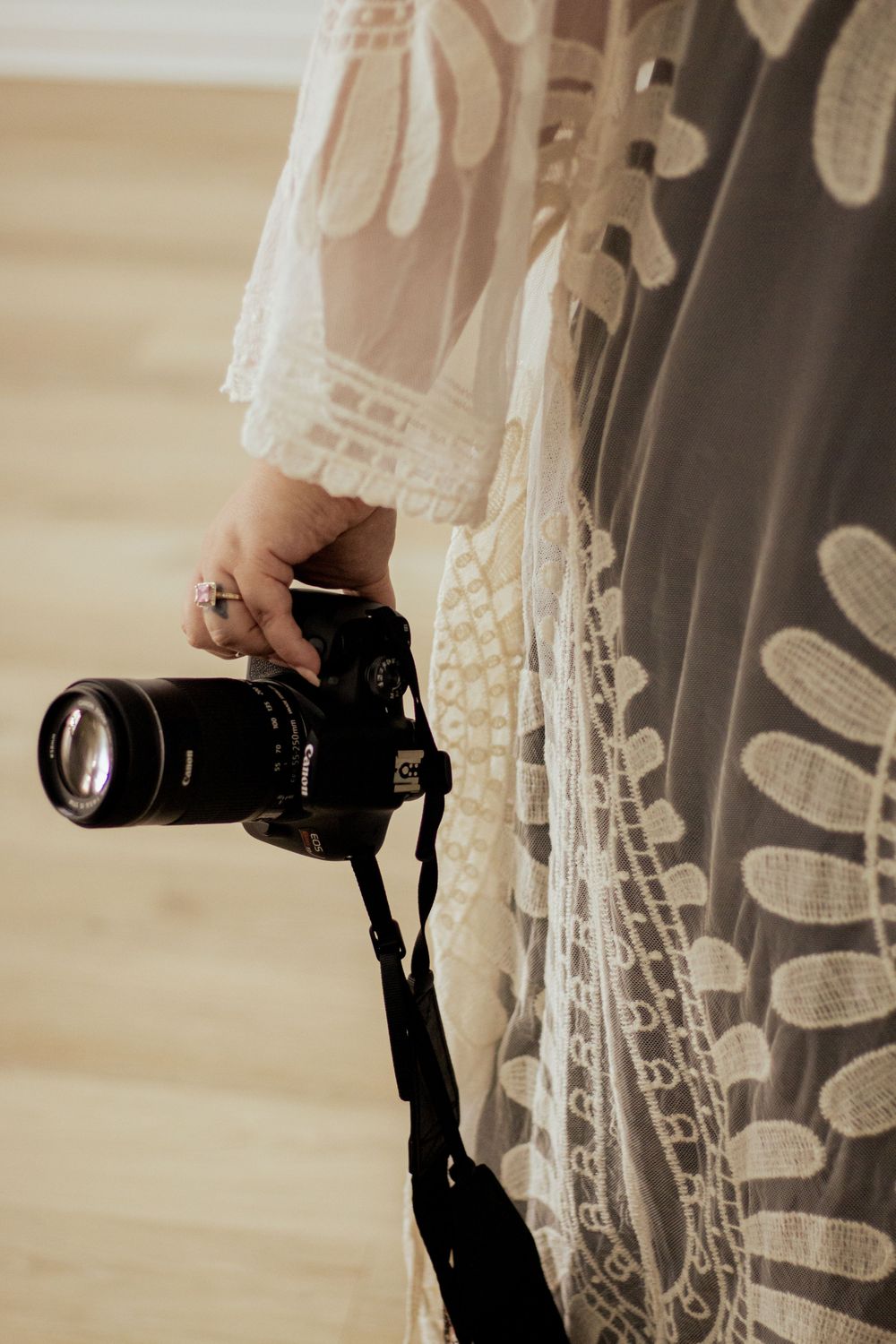 A black DSLR camera with extended lens is held against a textural patterned background at different angles.