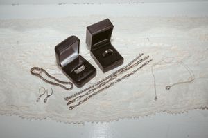 Collection of delicate jewelry pieces and necklaces displayed in brown jewelry boxes on a white surface.