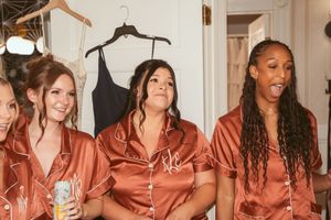 People wearing matching silk copper-colored sleepwear robes laugh together during a celebratory gathering.