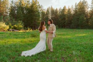 Scenic wedding photos captured in a grassy meadow with evergreen trees during golden hour.