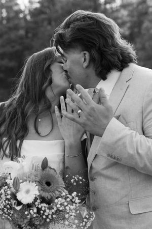 A romantic black and white portrait with a bouquet of flowers and intimate embrace.