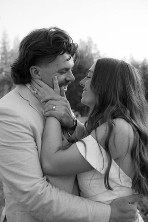 A romantic black and white photo of a couple sharing an intimate moment outdoors.